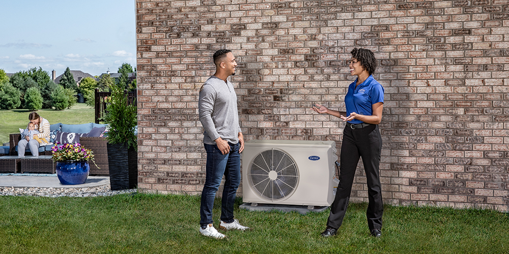 Tech in blue shirt explains to homeowner the benefits of A/C maintenance.